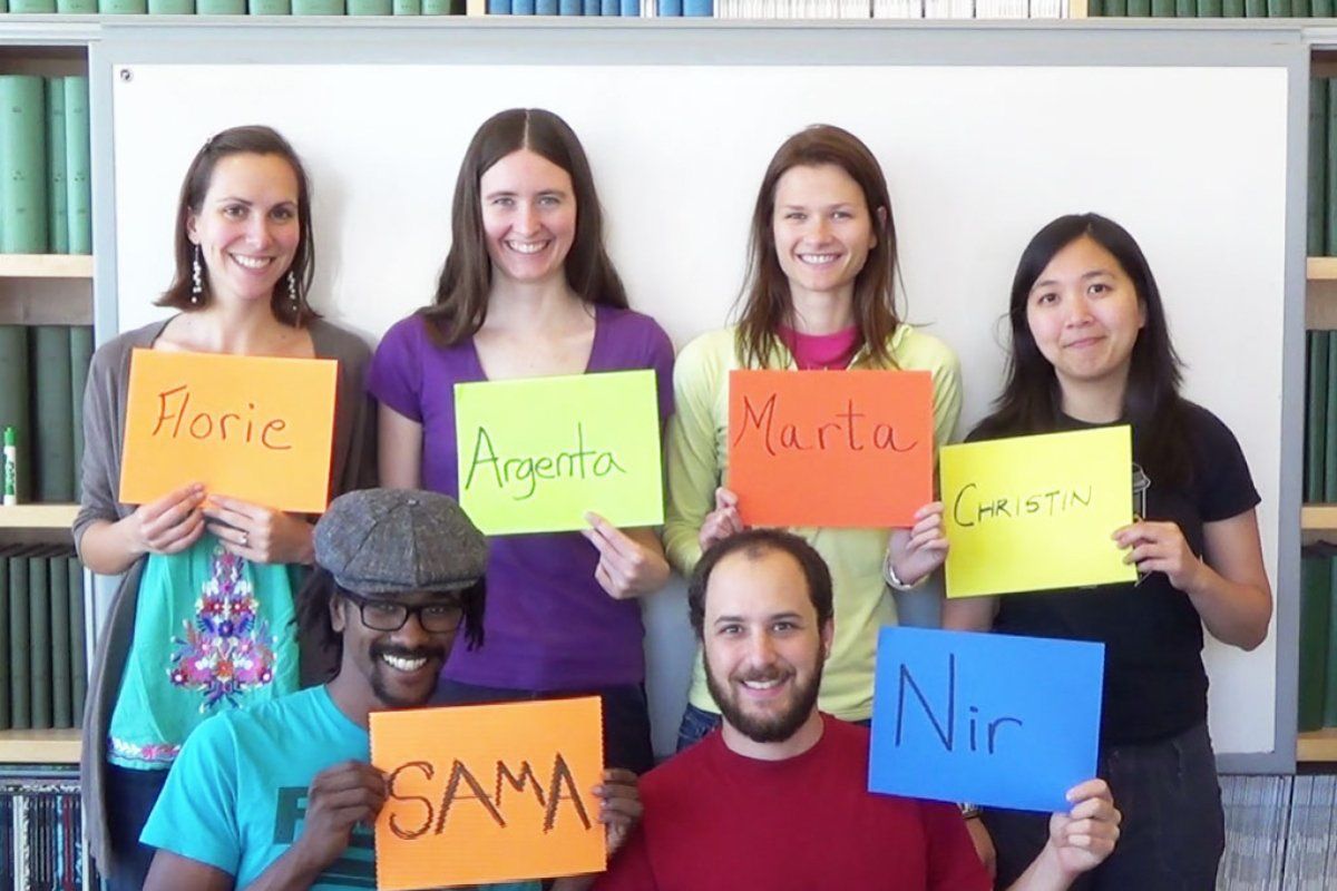 5 graduate students holding signs with their names