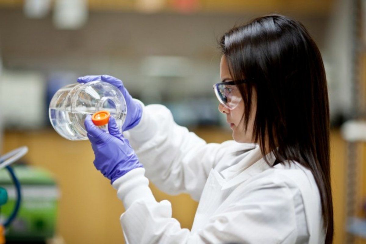 Medical student pouring liquid into beaker 