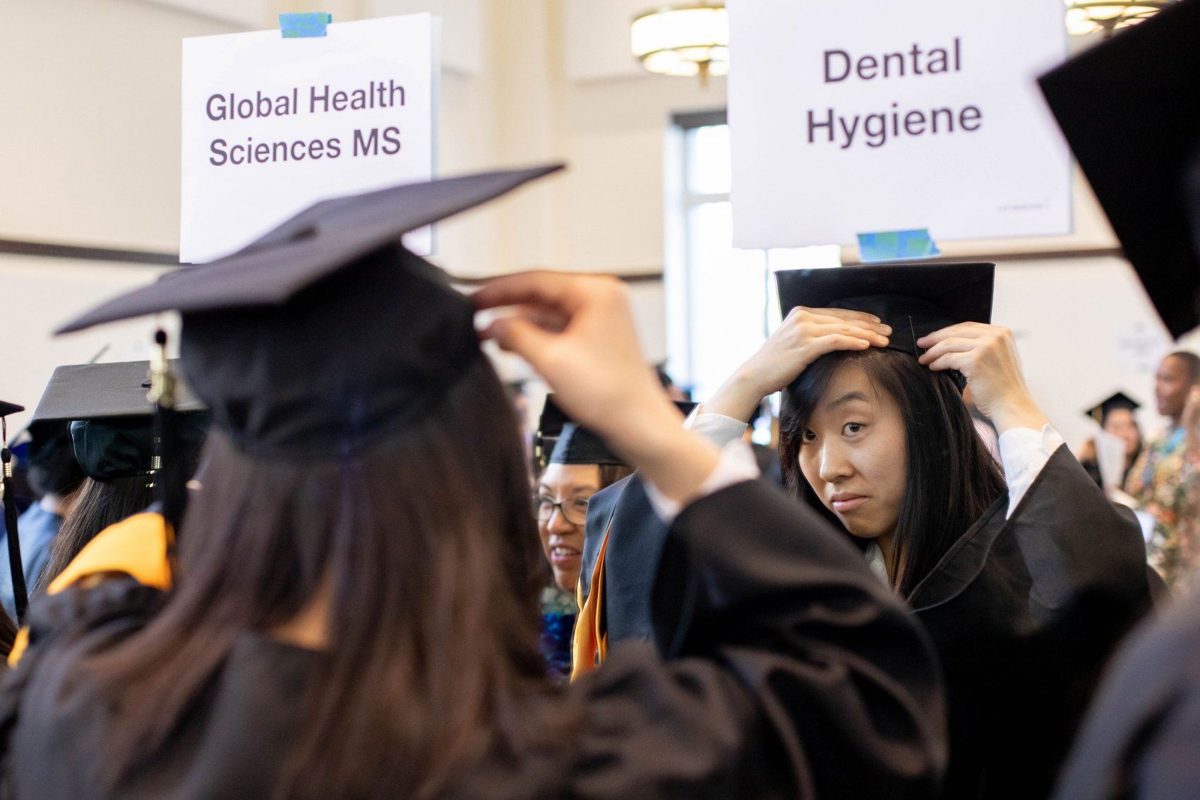 Student adjusts cap in mirror before Grad Div Commencment 2019
