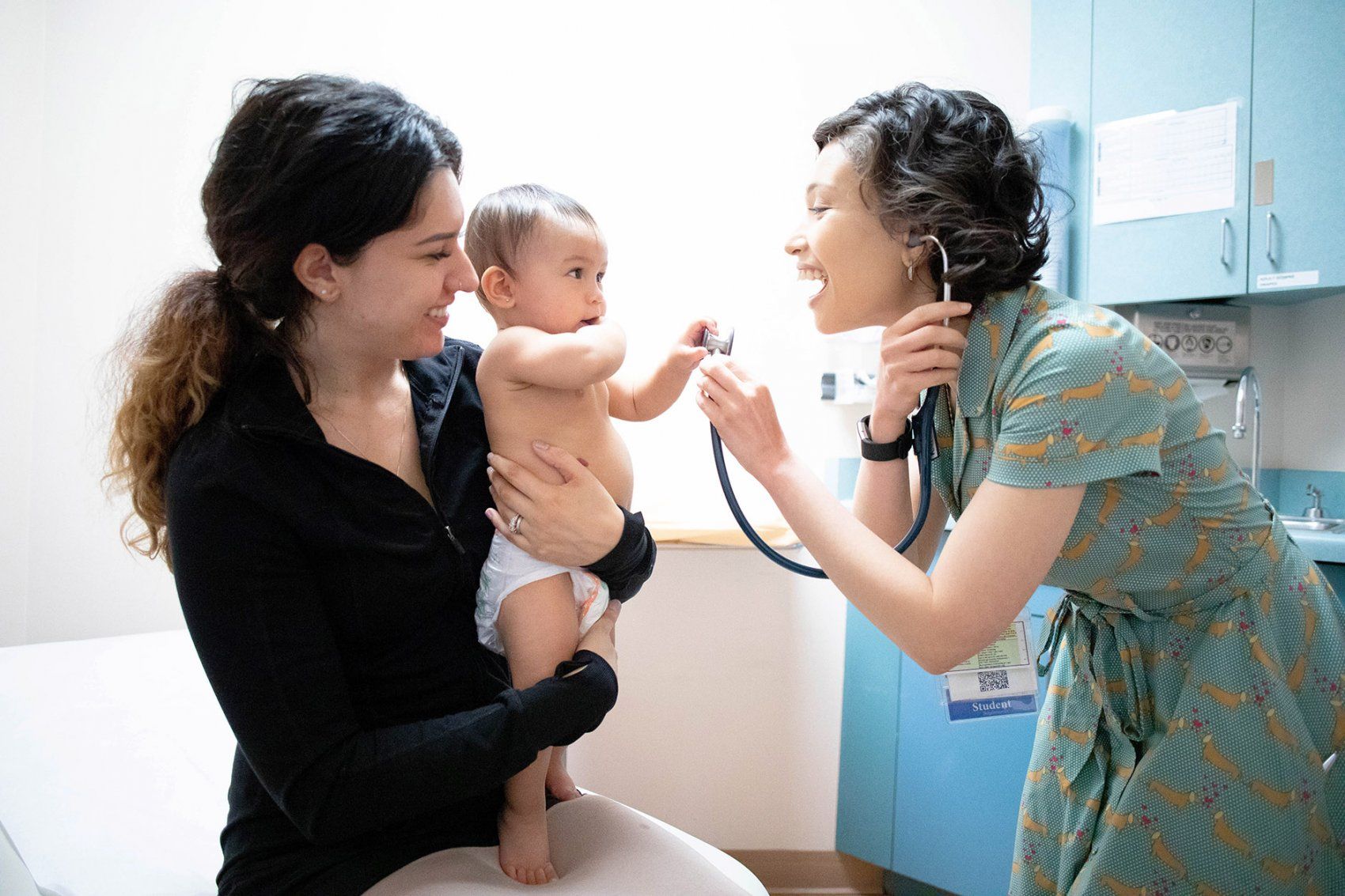 doctor holds up a stethoscope to an infant