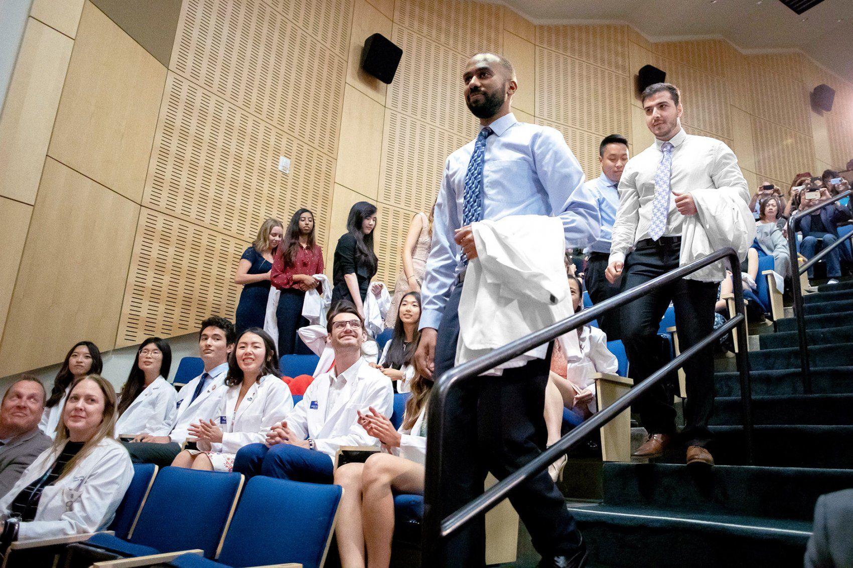 students walk down stairs in an auditorium