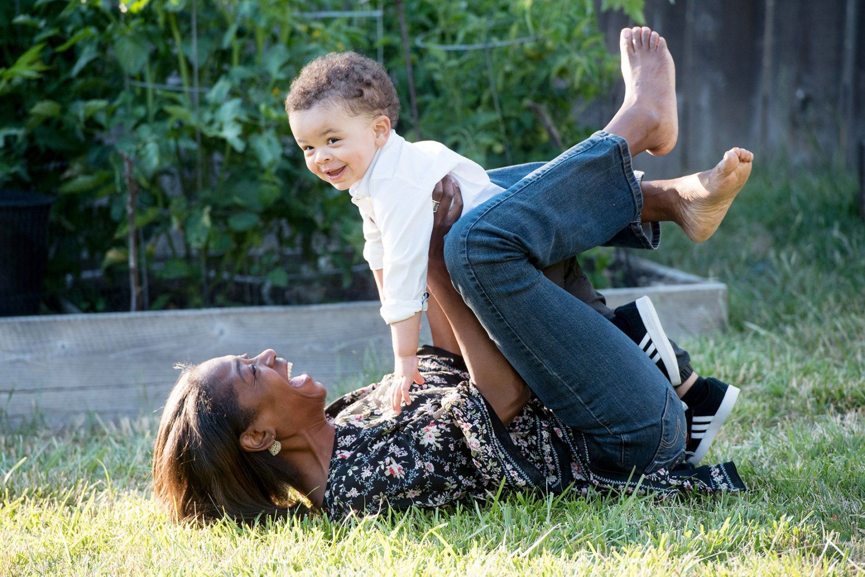 a mother holds her toddler while laying on grass