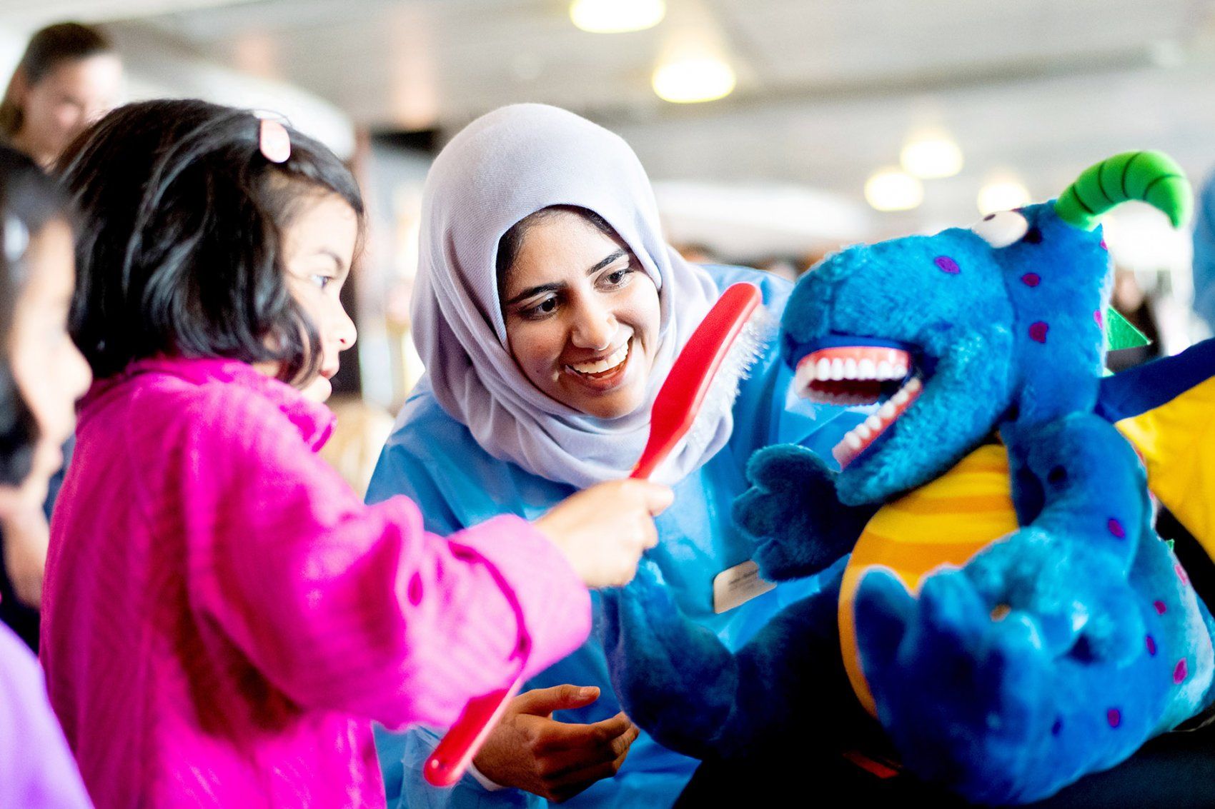 a girl brushes the teeth of a stuffed animal