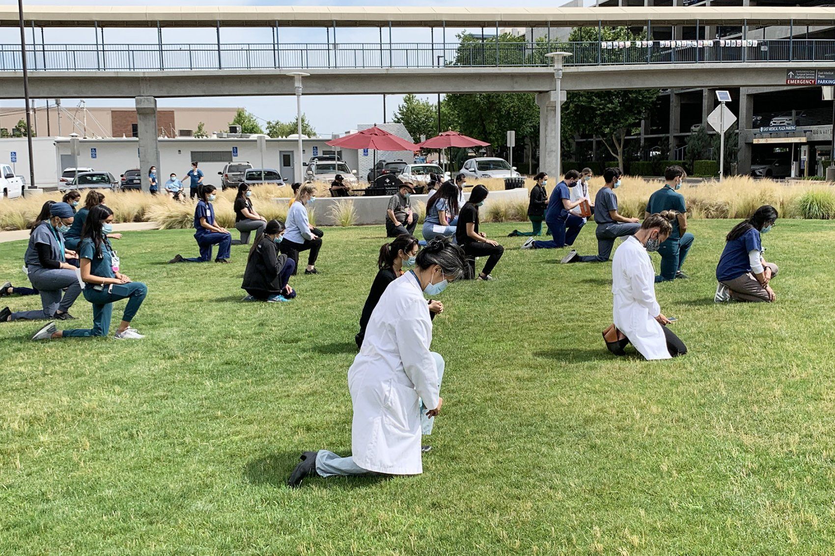 protestors kneel on a lawn at UCSF Fresno