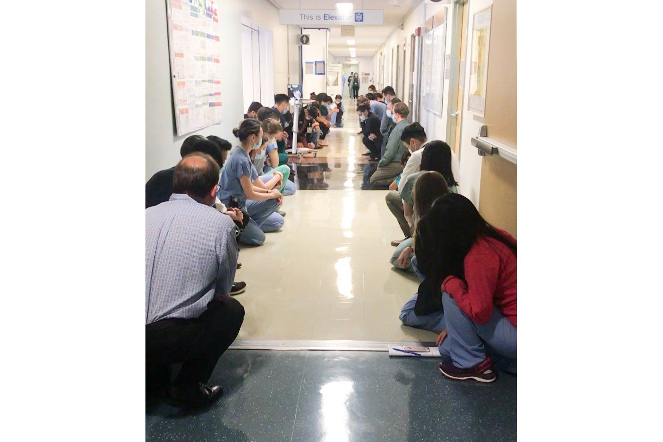 health care workers kneel in a hallway