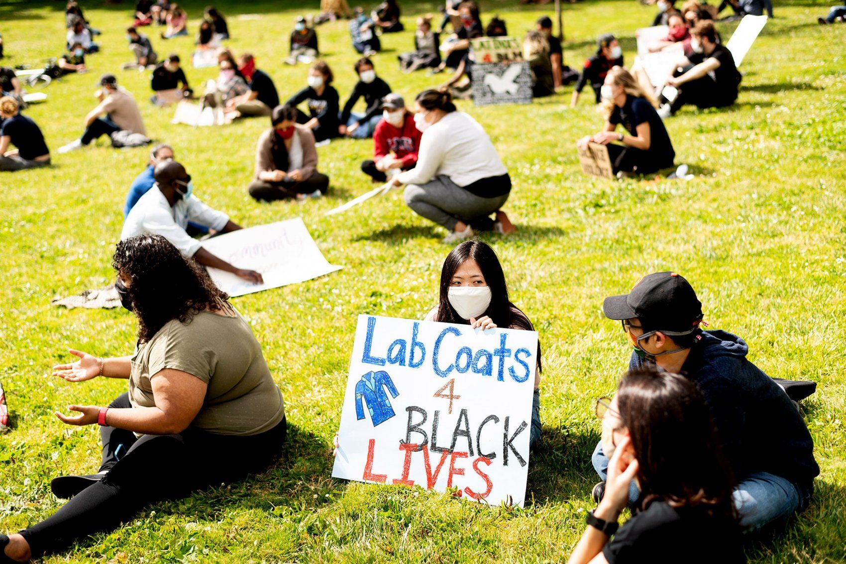woman holds Lab Coats for Black Lives sign at rally