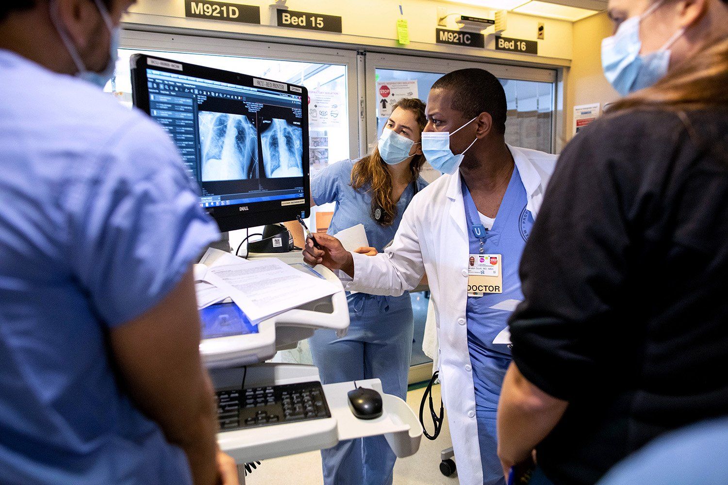 Nurses and doctors examine a scan of a patient's lungs on a monitor
