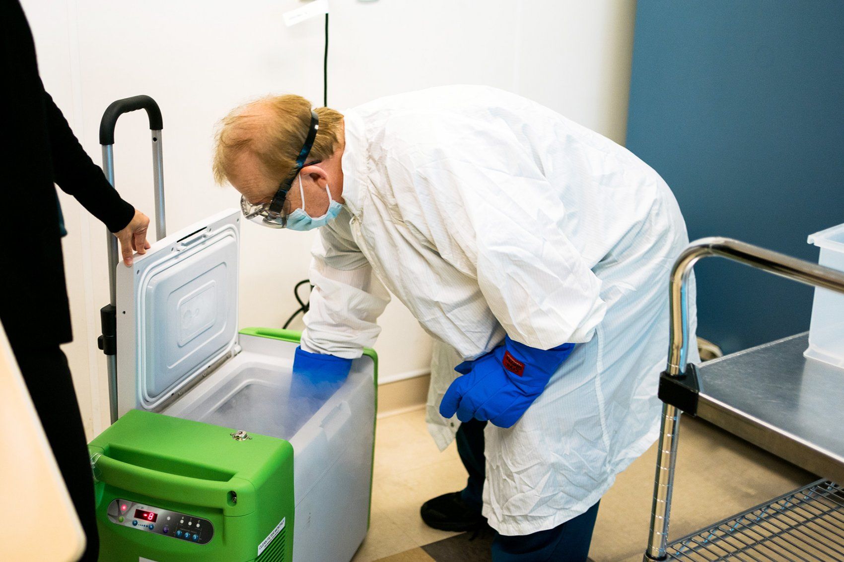 a pharmacy technician places the COVID-19 into a portable freezer