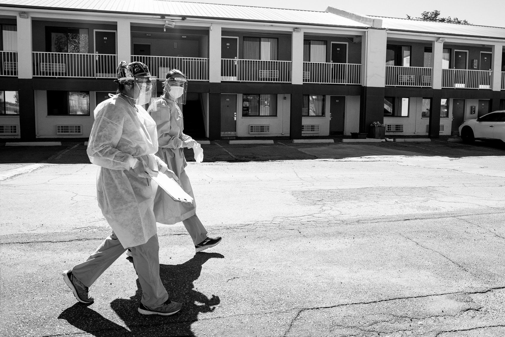 medical workers walk across a motel parking lot