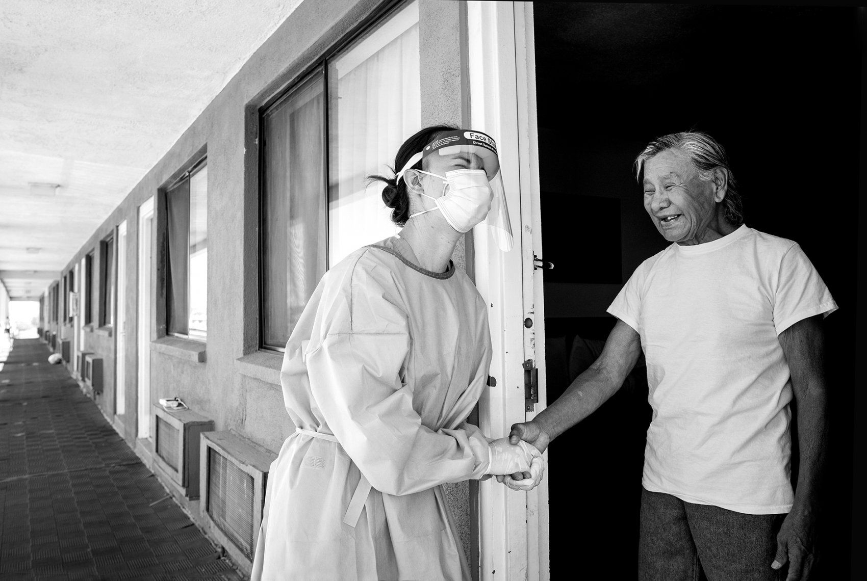 medical worker talks with a man in a motel doorway