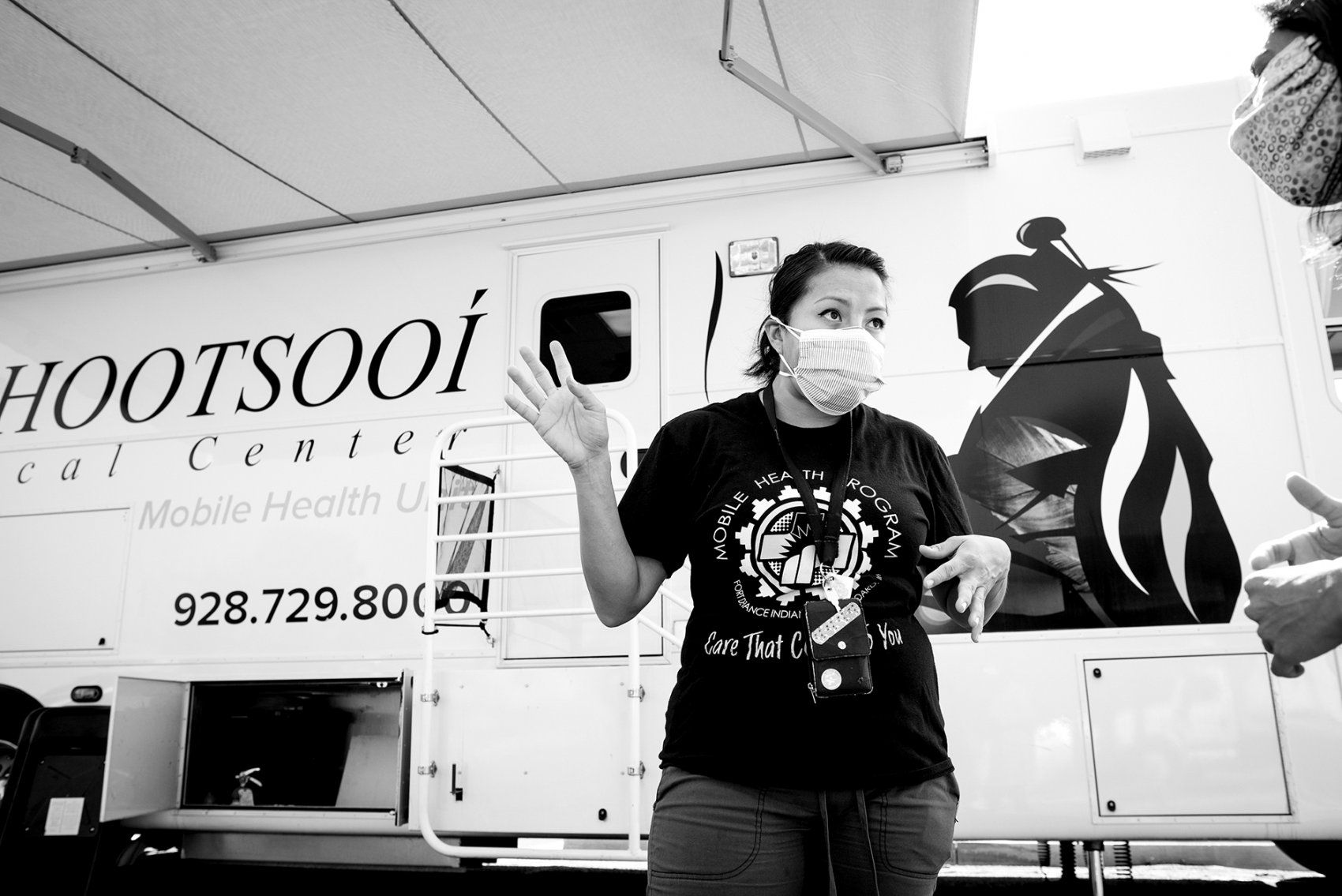 a female health care worker talks in front of a mobile clinic
