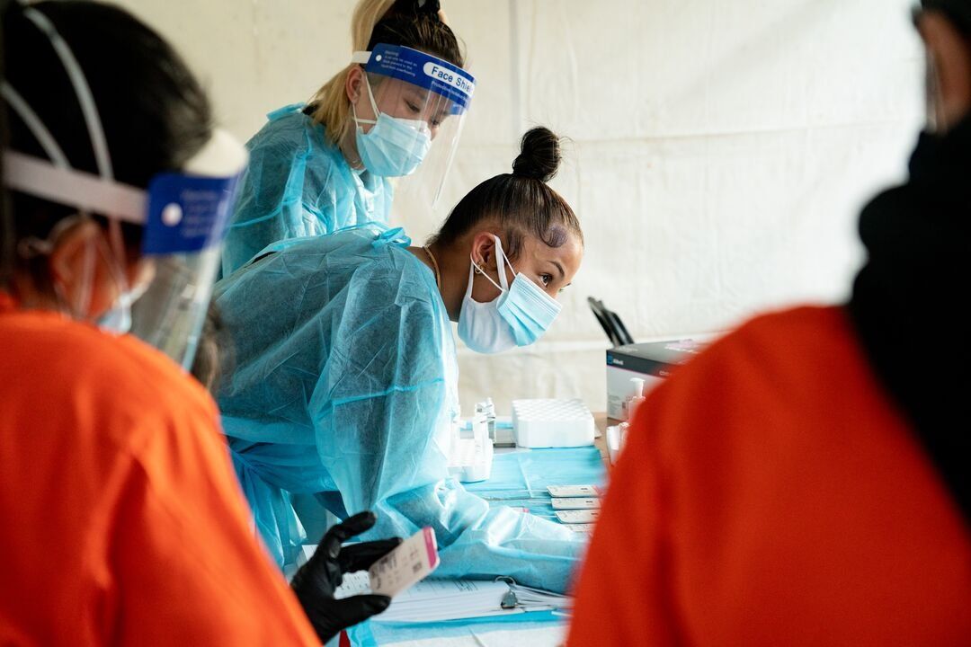 A nurse in scrubs and a face mask works at a community testing site