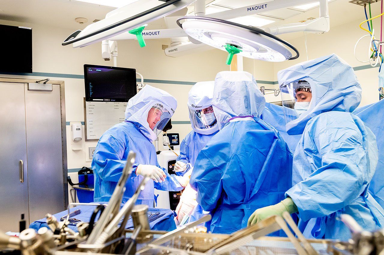A group of surgeons in an operating room lean over a table