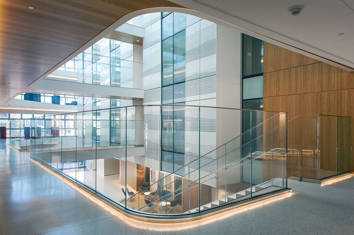 An interior shot of the Nancy Friend Pritzker Psychiatry Building. Glass lines the corridor, and wood paneling lines part of the roof and a wall.