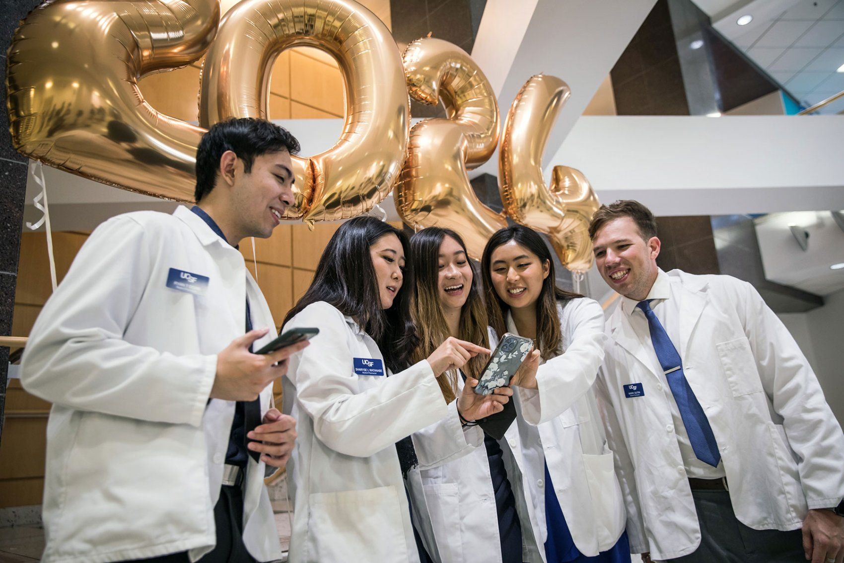 School of Pharmacy students gather for a photo under balloons that read 2024 during their white coat ceremony