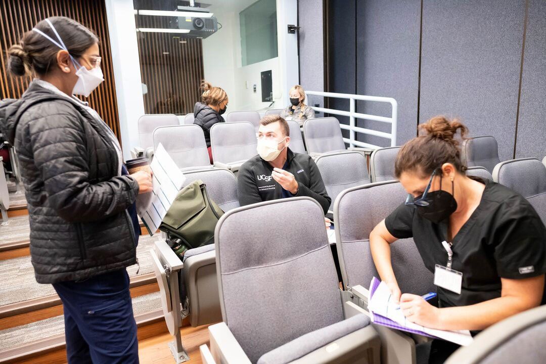 Three master's students in the school of nursing sit in an auditorium for a skills lab