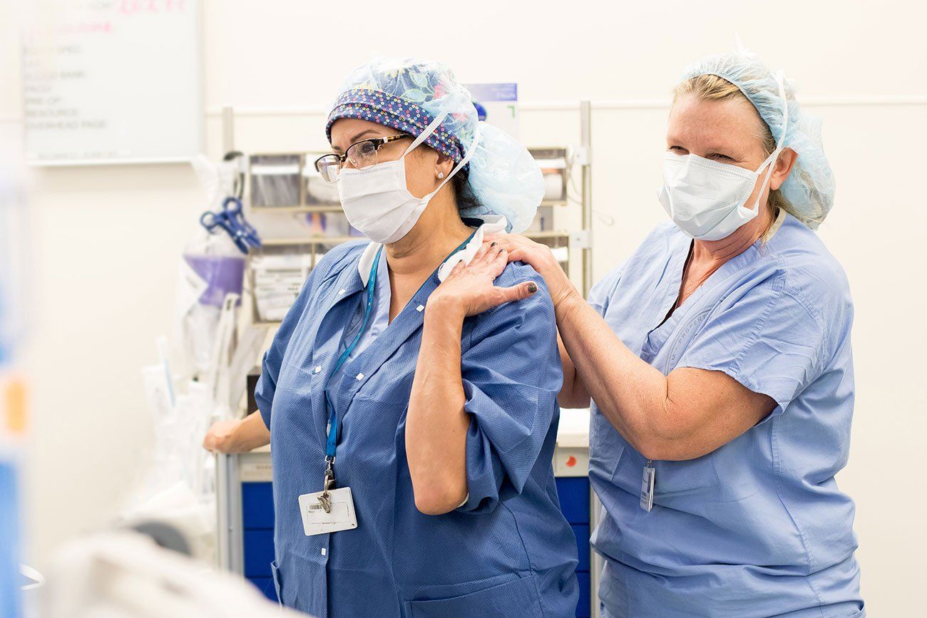 Two medical professionals in scrubs stand together during surgery