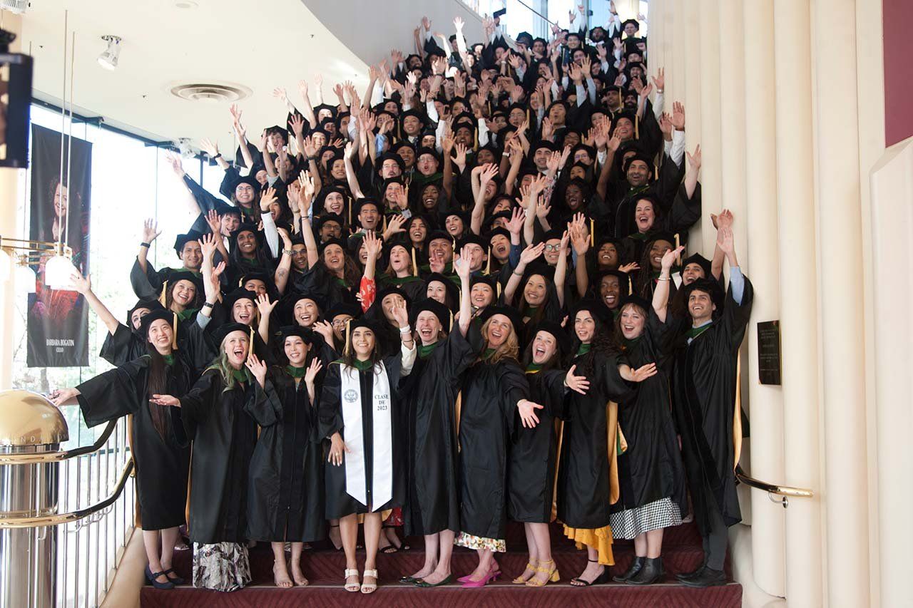 A large group of students poses on every step of a stairwell and cheers.