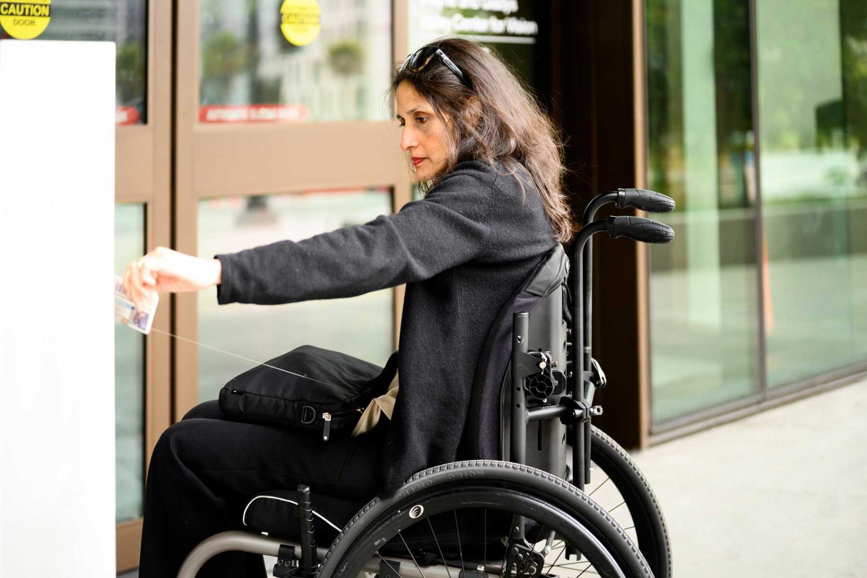 Janhavi Bonville swipes her credentials to enter a building in her wheelchair.