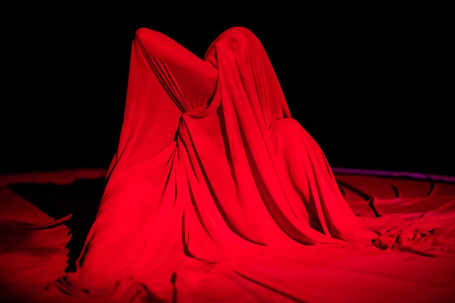 A woman poses under a sheer red cloth as part of Katina Bitsicas's art piece, "Blood Meal."