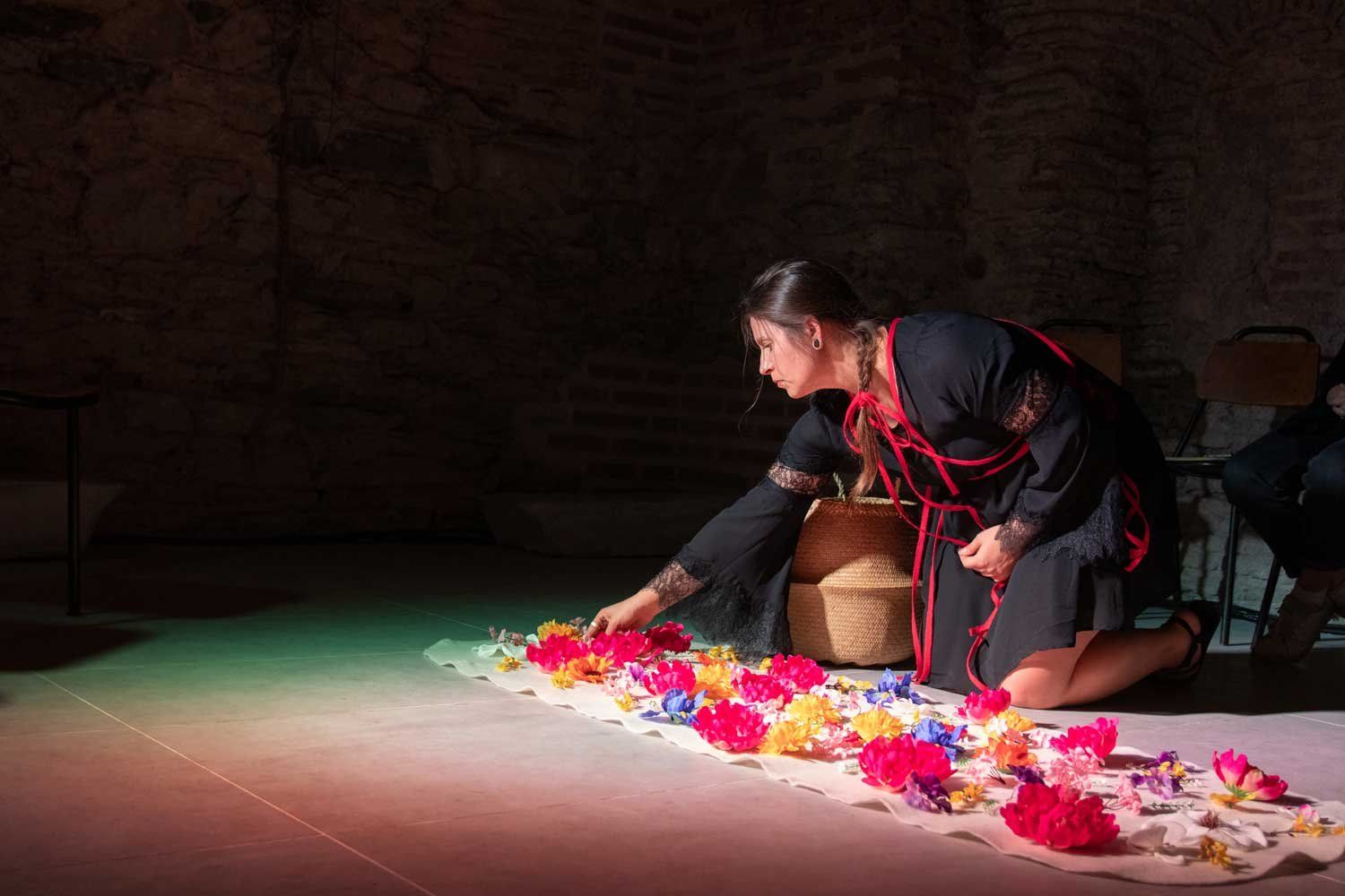 Katina Bitsicas kneels as she places flowers on a canvas spread on the floor, as part of her art installation "In Memoriam."