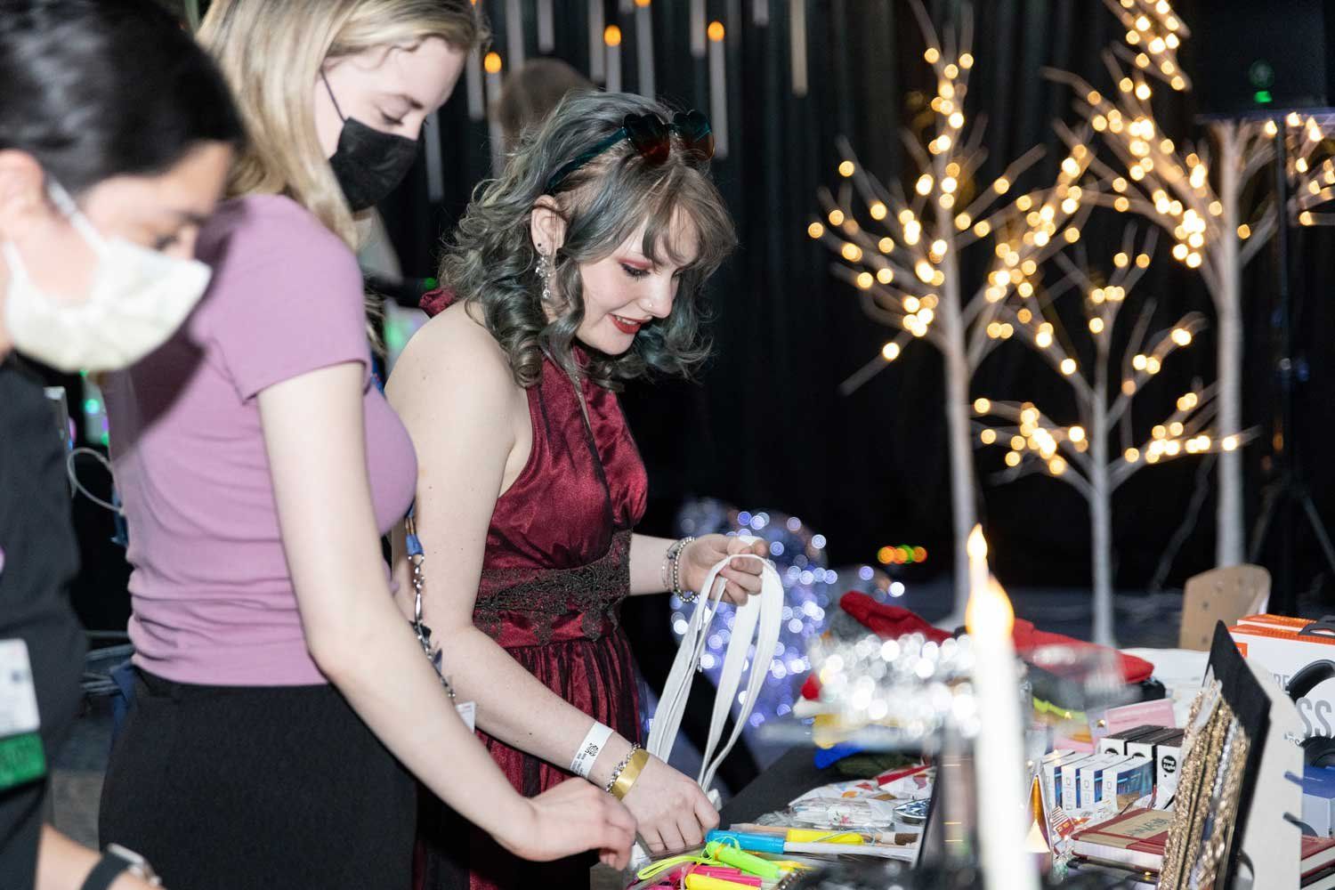 Teen prom guests look through a table of freebies such as notebooks and markers.