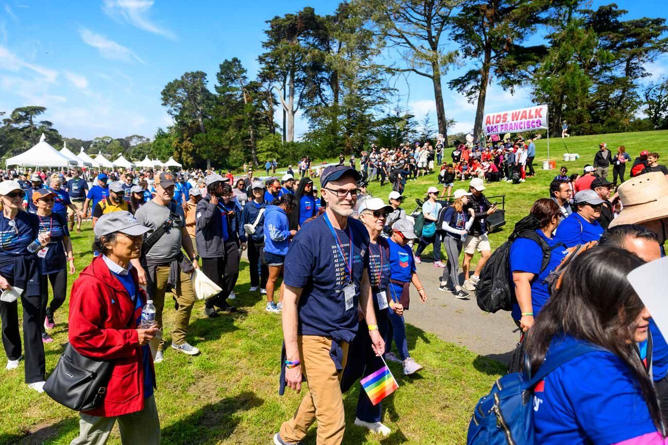 Attendees stand and walk outdoors at the 2023 AIDS walk event.