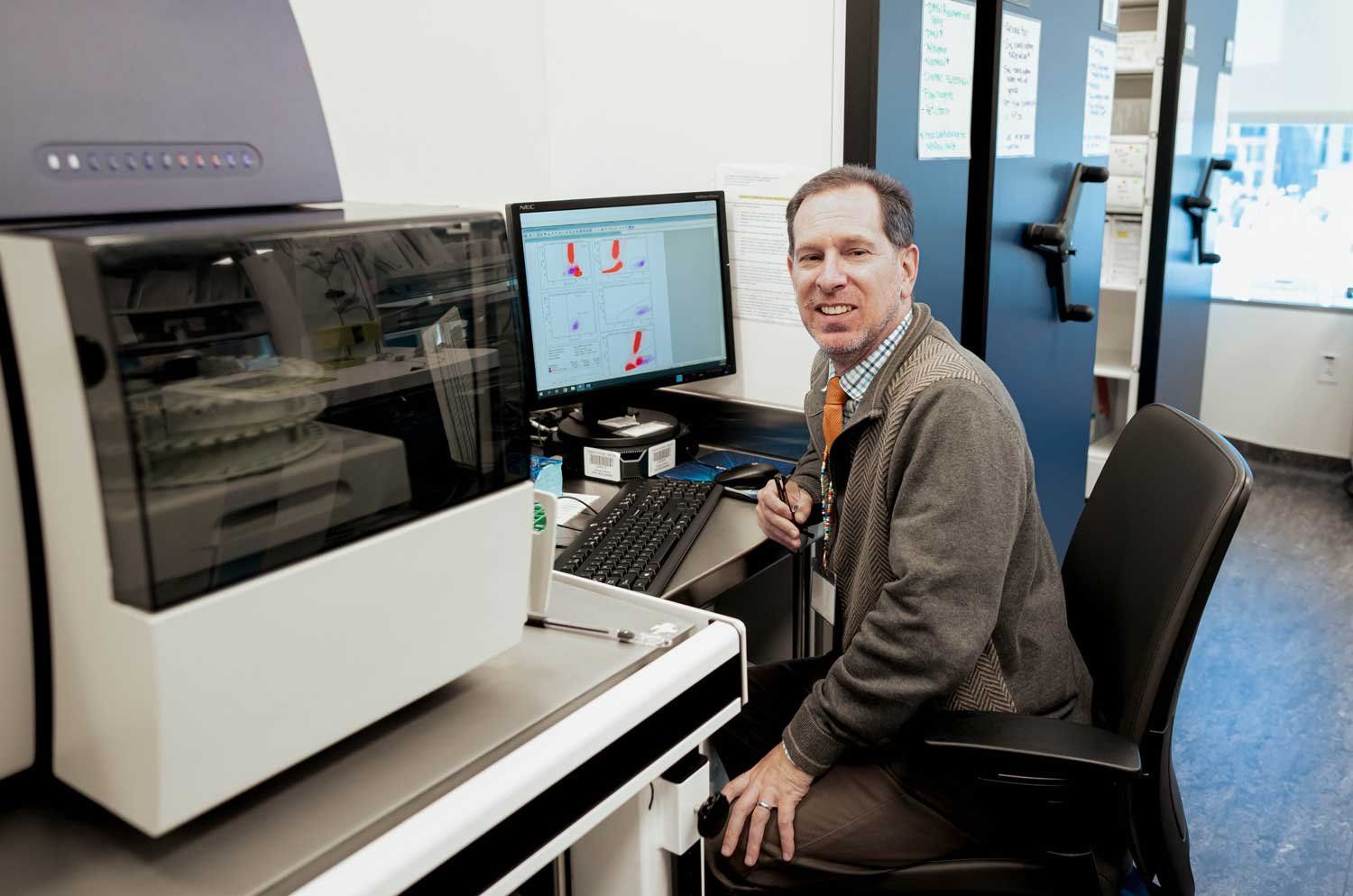Dr. Christopher Dvorak sits at his desk analyzing graphs on a computer.
