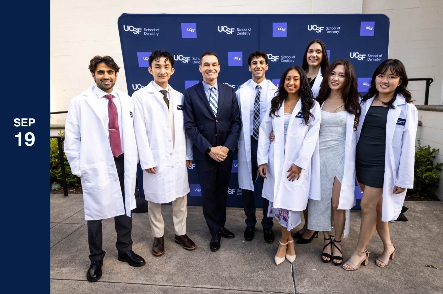 Group of students in white coats in front of UCSF step and repeat.