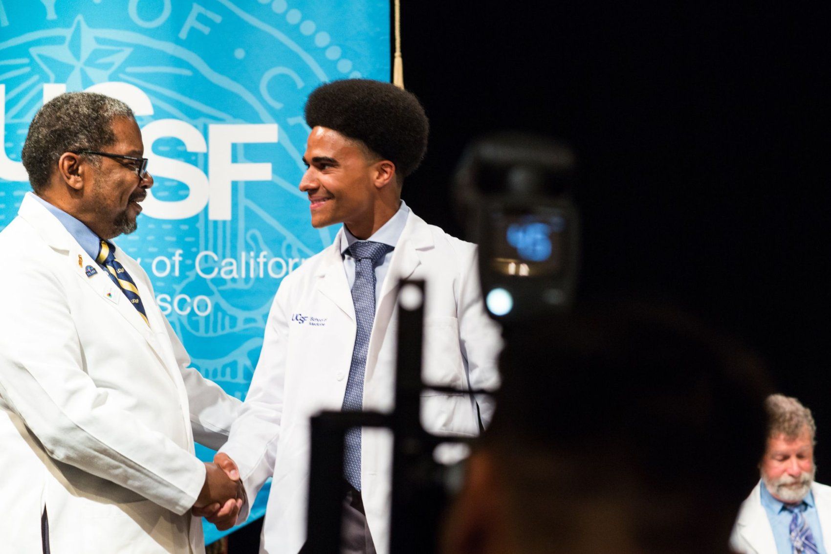 Talmadge shakes the hand of student on stage.