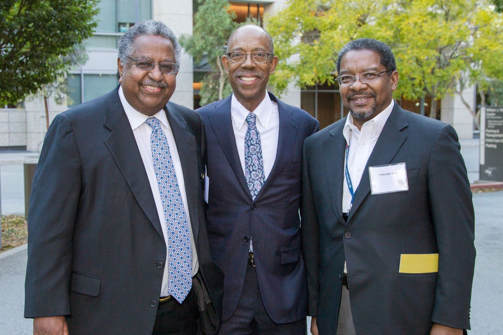 Talmadge poses with two other colleagues in suits.