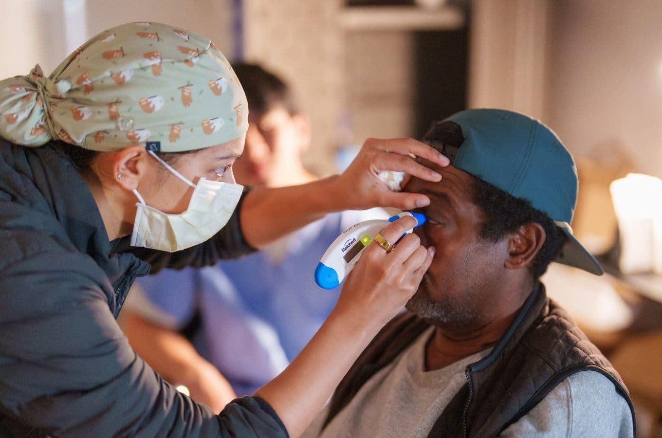 A health professional conducts an eye exam on a middle-aged male patient.