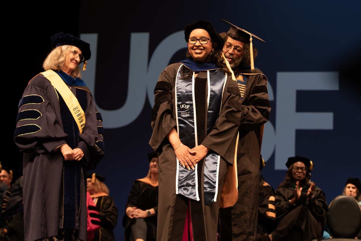 Graduate being hooded on stage during commencement.
