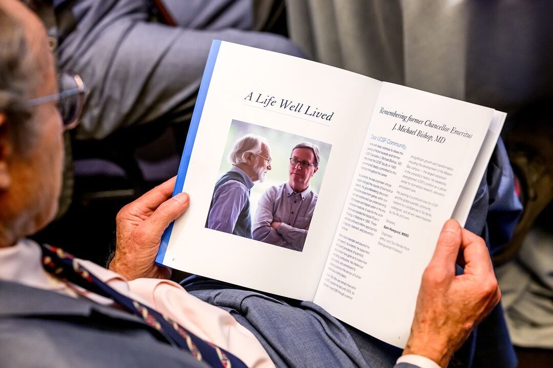 An attendee holds a printed program for J. Michael Bishop's memorial.