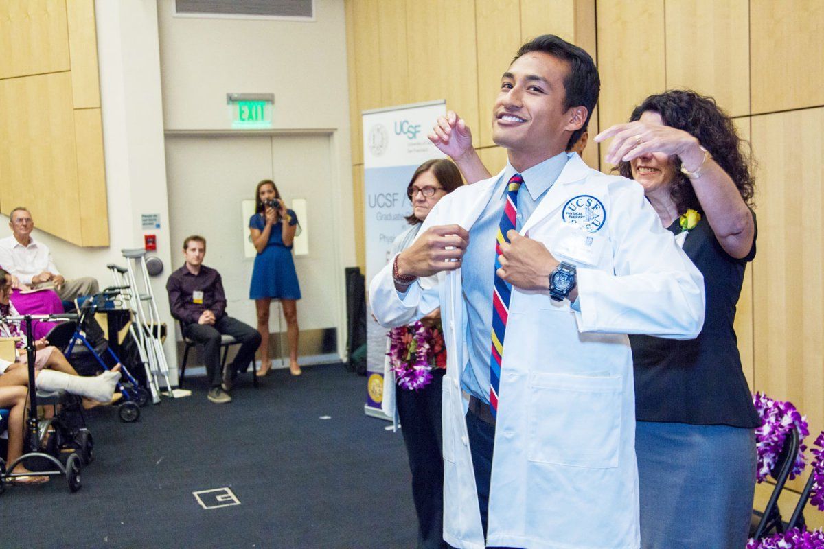 physical therapy student Wesley Briones smiles as he's cloaked during white coat ceremony by Kimberly Topp, PT, PhD