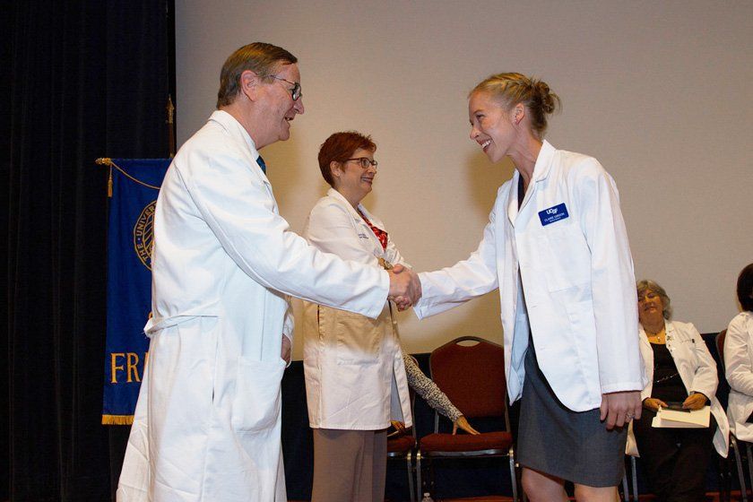 Sam Hawgood, MBBS, congratulates Claire Gibson during the White Coat ceremony