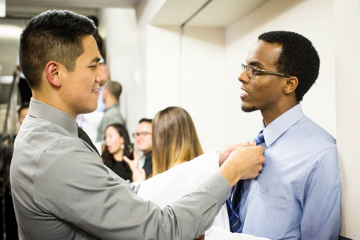 Kyle Jureidini adjusts Samuel Zemede’s tie ahead of the Department of Physical Therapy and Rehabilitation Science white coat ceremony