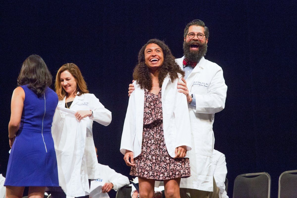 School of Medicine student Sheyda Aboii receives her white coat from John Davis, MD, PHD