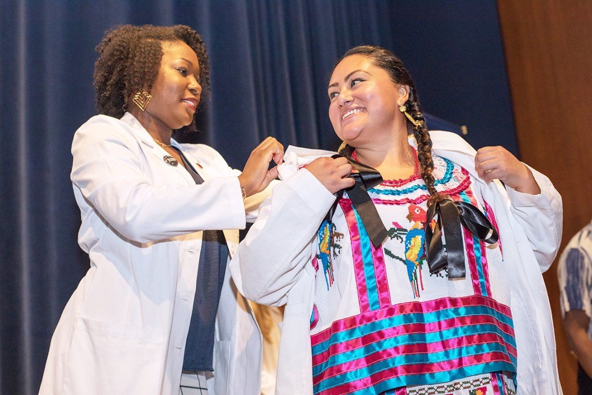 Elisa Ortega-Enriquez is receiving her white coat from Camyl Anderson