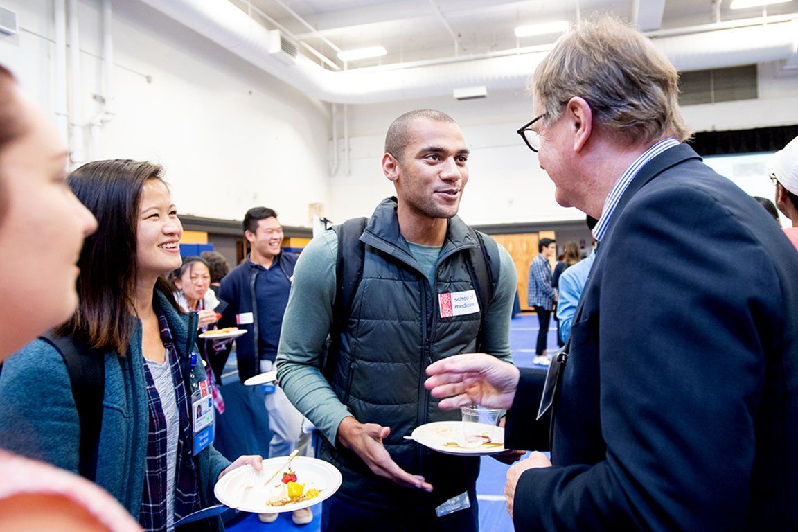 UCSF Chancellor Sam Hawgood, MBBS, speaks with Chance Shaw, a first-year in the UCSF School of Medicine, and other students at a reception held at the Millbery Union Gym.