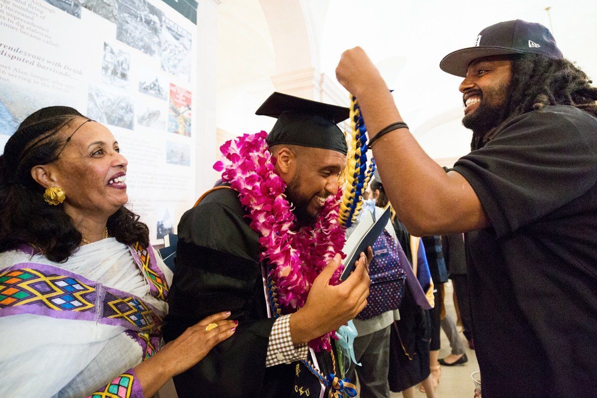 Samuel Russom receives leis from his family at the School of Dentistry commencement ceremony