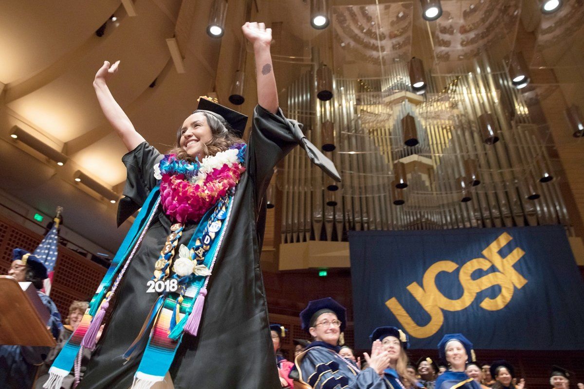Gabriela Chica raises her arms in celebration at the School of Nursing commencement ceremony