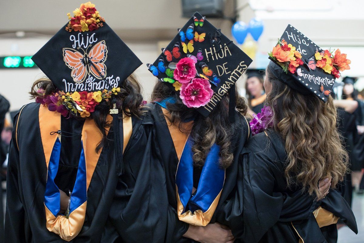 Gabriela Chica, Vanessa Gutierrez and Brenda Lopez wear decorated mortarboards that say “daughter of immigrants” at the school’s commencement ceremony