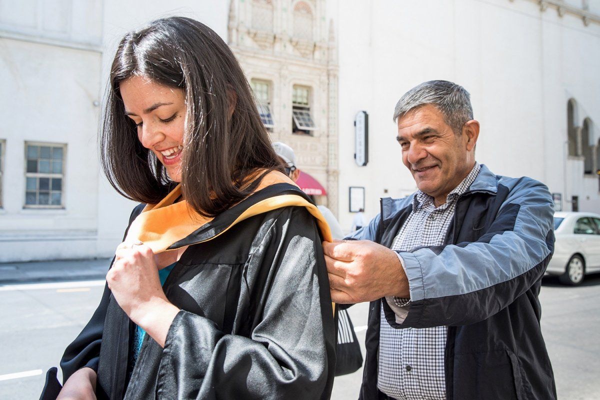Laili Falattonzadeh adjust her hood at the School of Nursing commencement ceremony