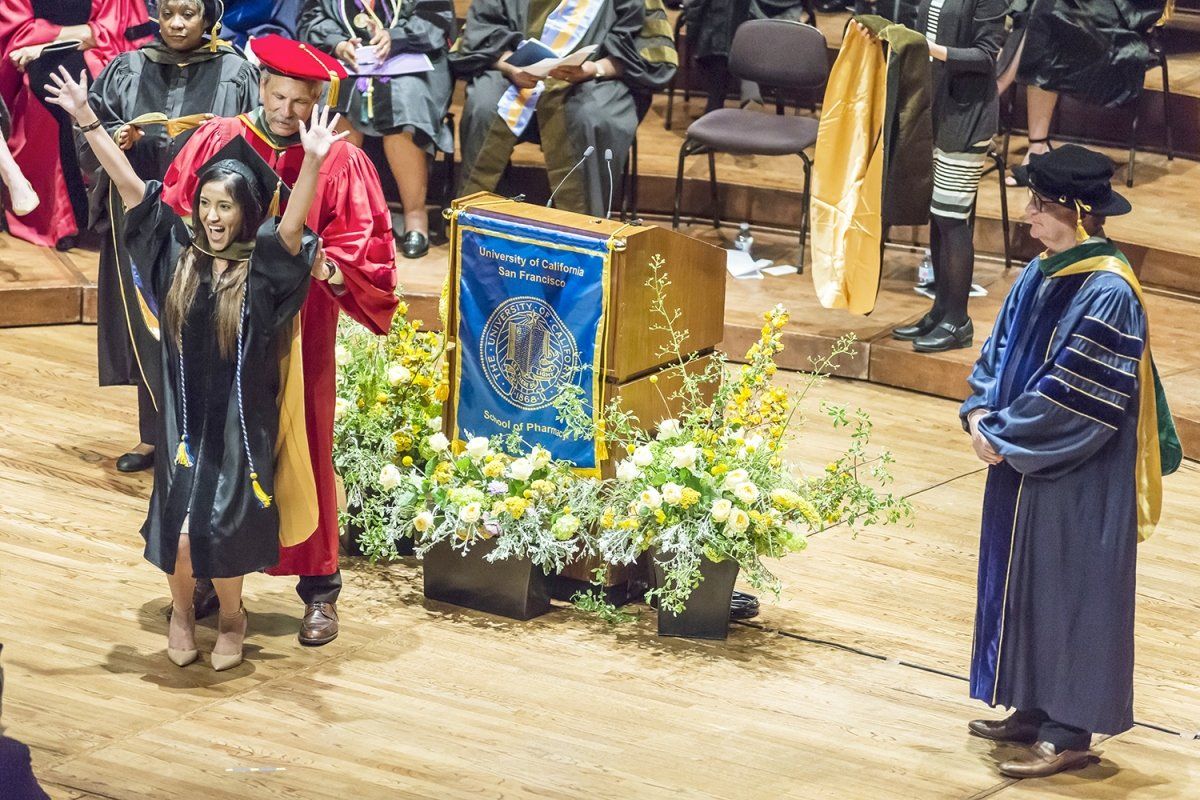 Lizeth Rivera receives her hood from School of Pharmacy Dean B. Joseph Guglielmo, PharmD, during the school’s commencement ceremony.