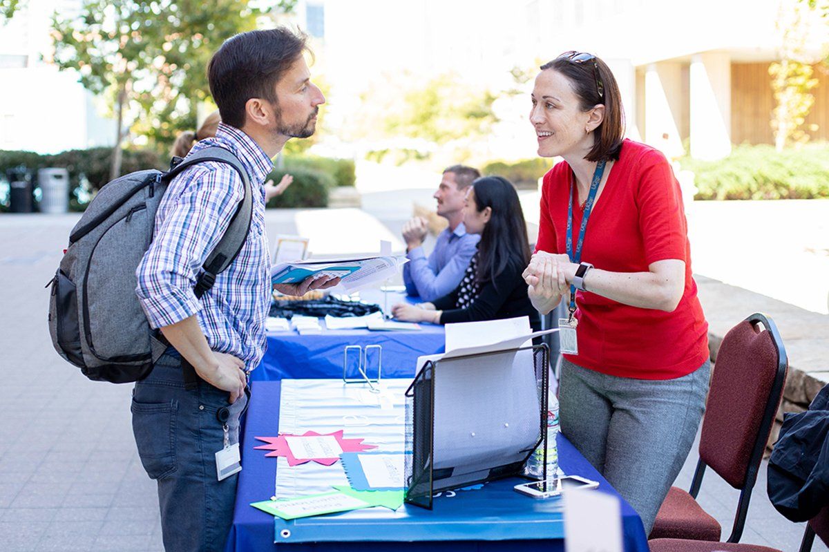 Ernesto Diaz Flores, PhD talks with Joan Doherty Campbell at her department’s informational kiosk during the Faculty Development Day conference.