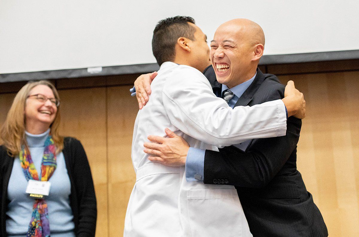 New Physical Therapy student Edward Hernandez embraces Kenneth Leung, DPT, assistant clinical professor of Physical Therapy, during a white coat ceremony