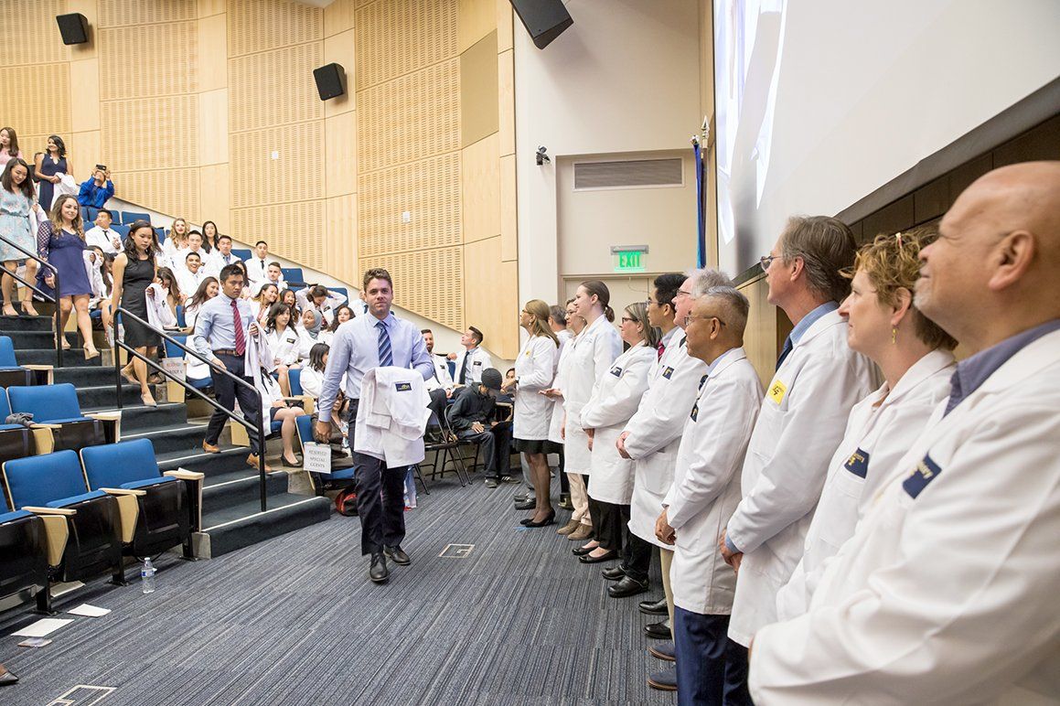 New School of Dentistry students walk down the stairs at Cole Hall during the school’s white coat ceremony.