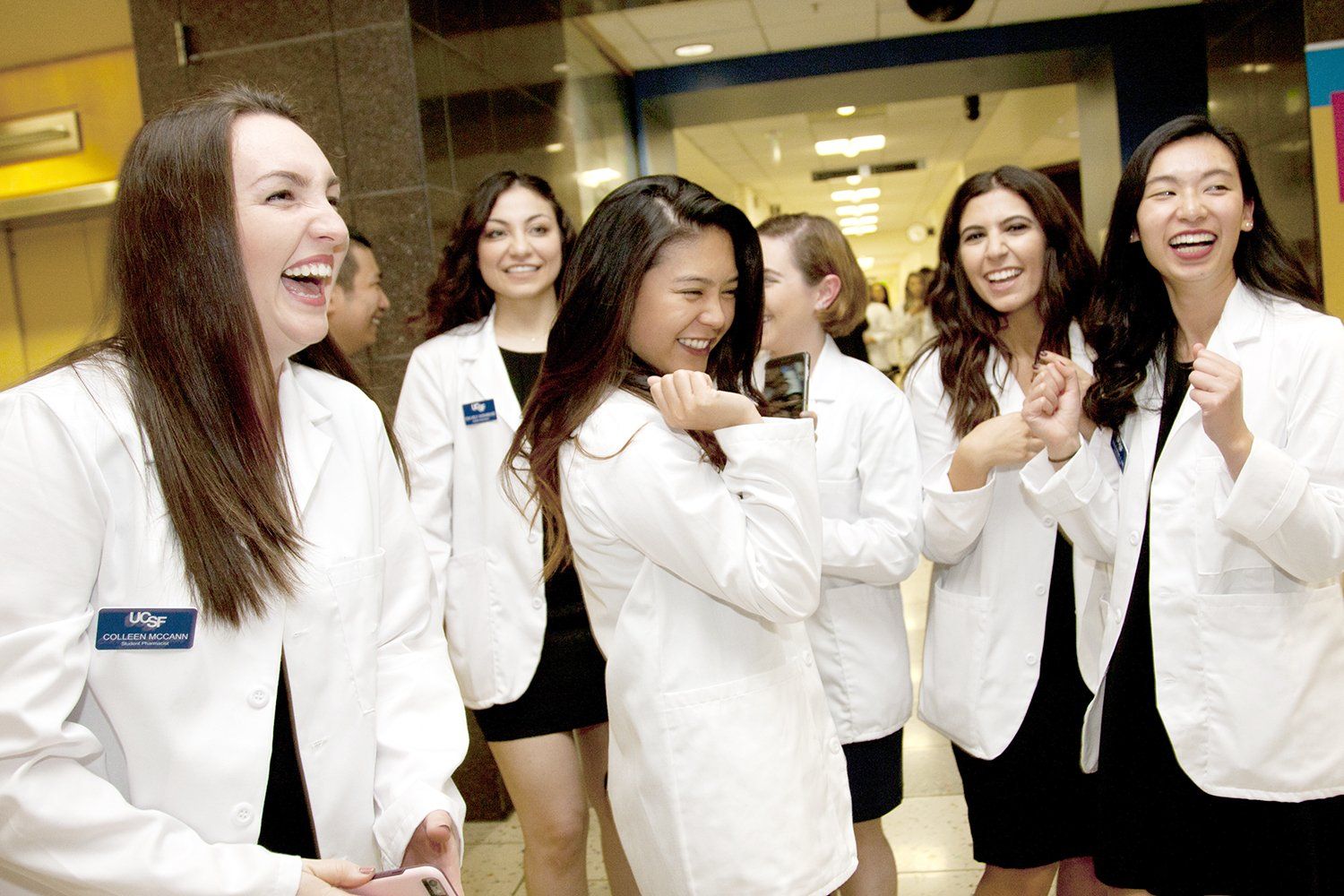 A group of new School of Pharmacy students laugh in their white coats