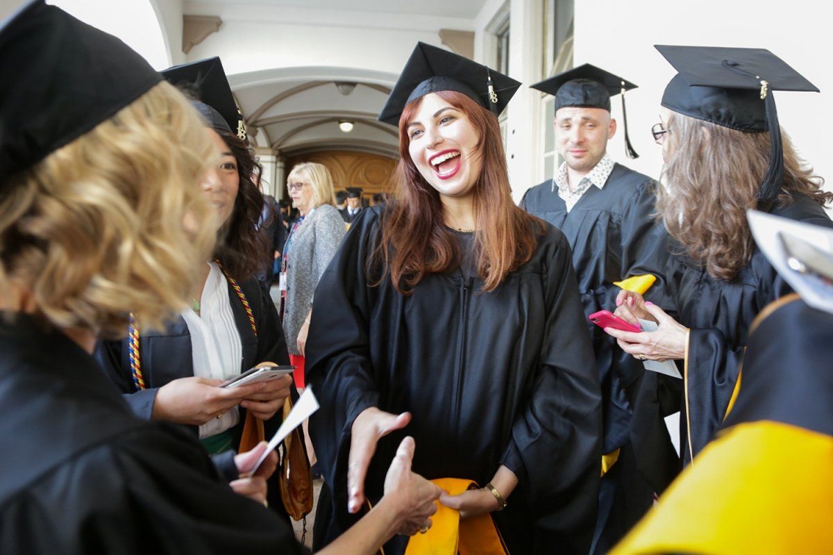 Leona Rajaee greets a fellow graduate at the Graduate Division’s commencement ceremony